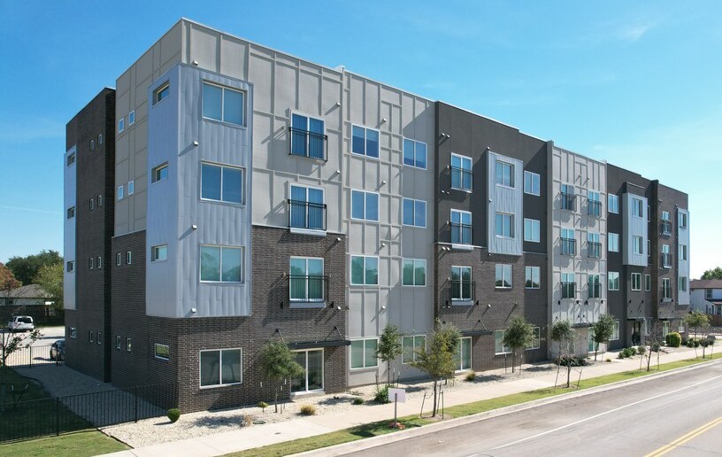 A modern apartment building with a mix of brick and panel exterior.